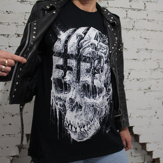 Lady in studded black leather jacket wearing this black t-shirt with large print of skull with a cryptid creature with tentacles and wing pushing out of the forehead region.